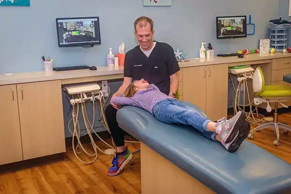 Dr. Eric Jacobsen happily talking with a young patient in the chair.