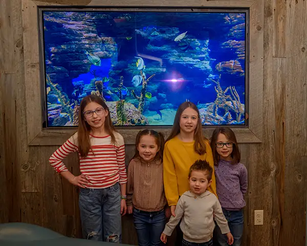 Some happy young patients standing in front of the aquarium at Jacobsen Pediatric Dentistry