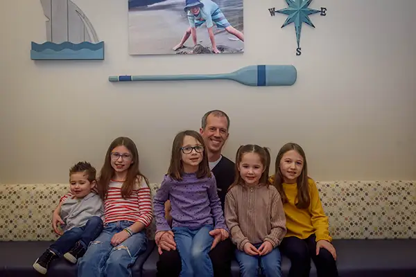 Dr. Eric Jacobsen sitting on waiting area couch with some happy young patients.