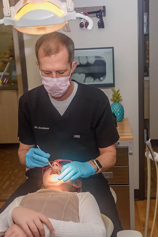 Dr. Eric Jacobsen taking a look at the tooth of a young girl in the chair. 