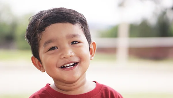 Young child smiling at the camera with only a few teeth