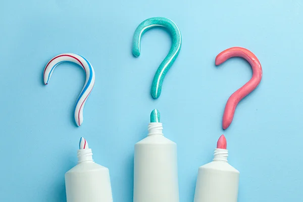 Different toothpaste tubes forming question marks with the paste