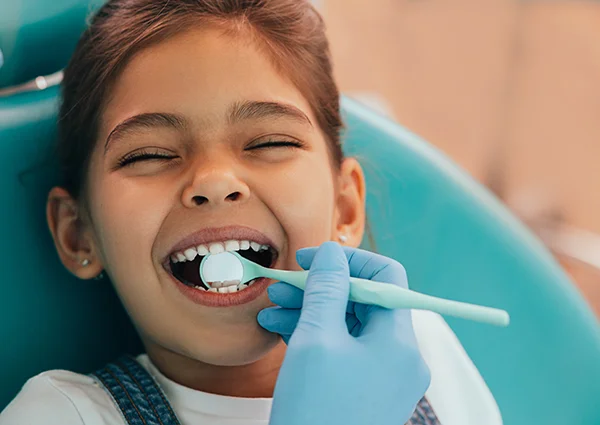 Kid smiling with dental mirror in mouth