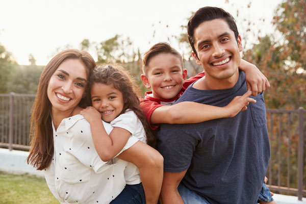 Young family smiling with a child on each parents back