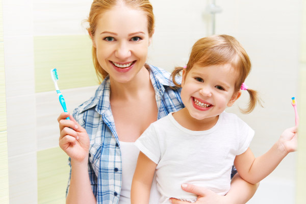 Mother and daughter smiling after brushing their teeth at Jacobsen Pediatric Dentistry in Oregon City, OR